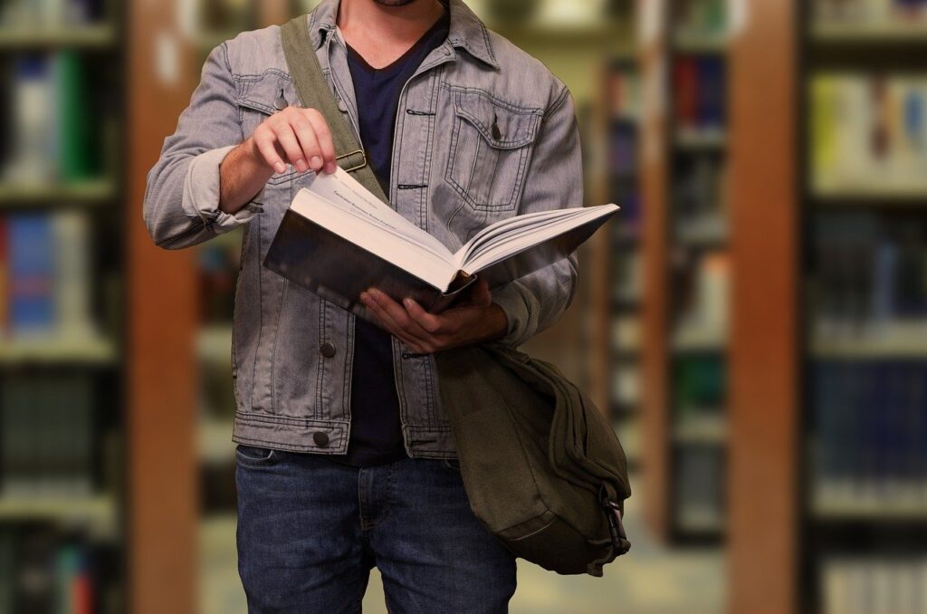 Photo représentant un étudiant avec un livre dans les mains.