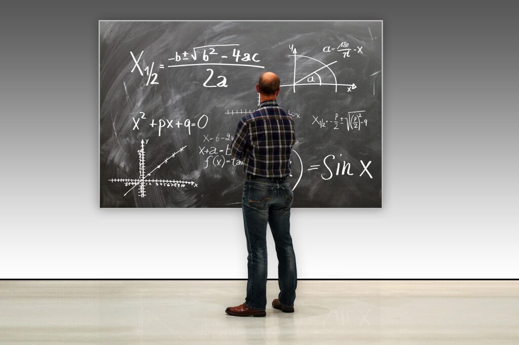 Photo représentant un enseignant devant un tableau noir comportant des équations mathématiques.